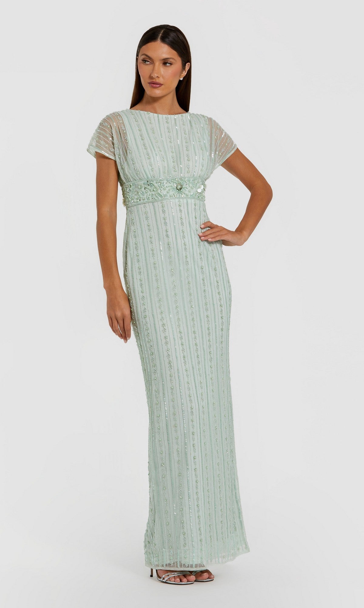 A woman poses against a plain white background wearing the Mac Duggal 94147 Long Formal Dress in sage—a floor-length gown featuring short sleeves, vertical beaded pearl embellishments, and a fitted waist.